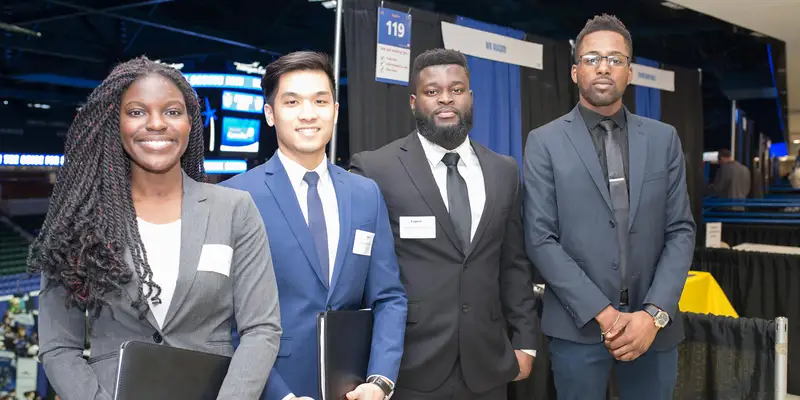 A female student and three male students in business suits
