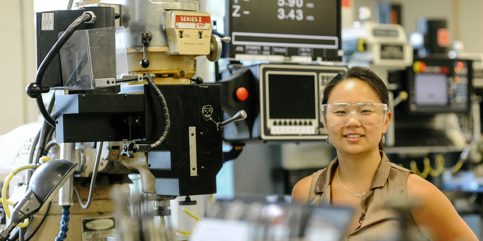 Asian woman wearing goggles in machine lab