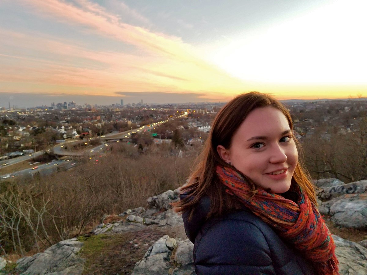 UMass Lowell student Aisling McEleney poses in front of a landscape view of a city