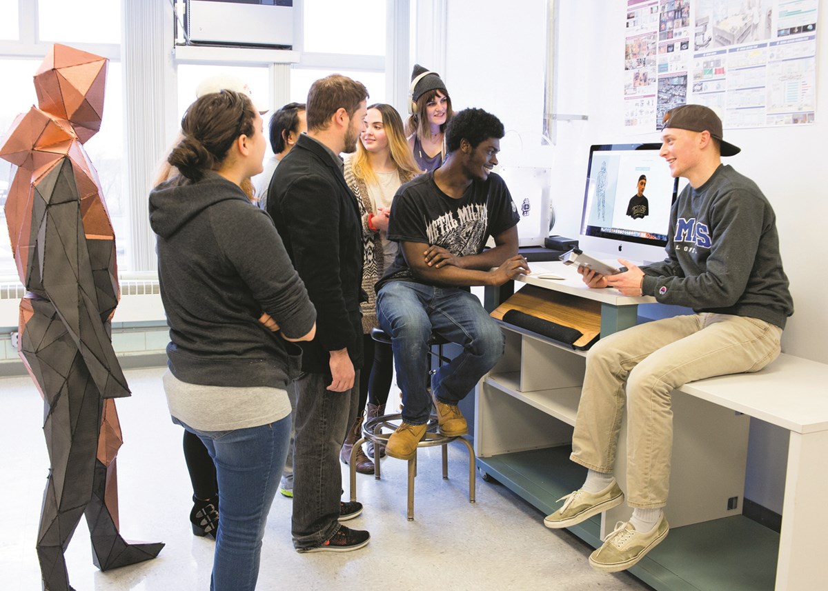 Art and design students around a computer at the new Expanded Media Fabrication Laboratory in Dugan Hall