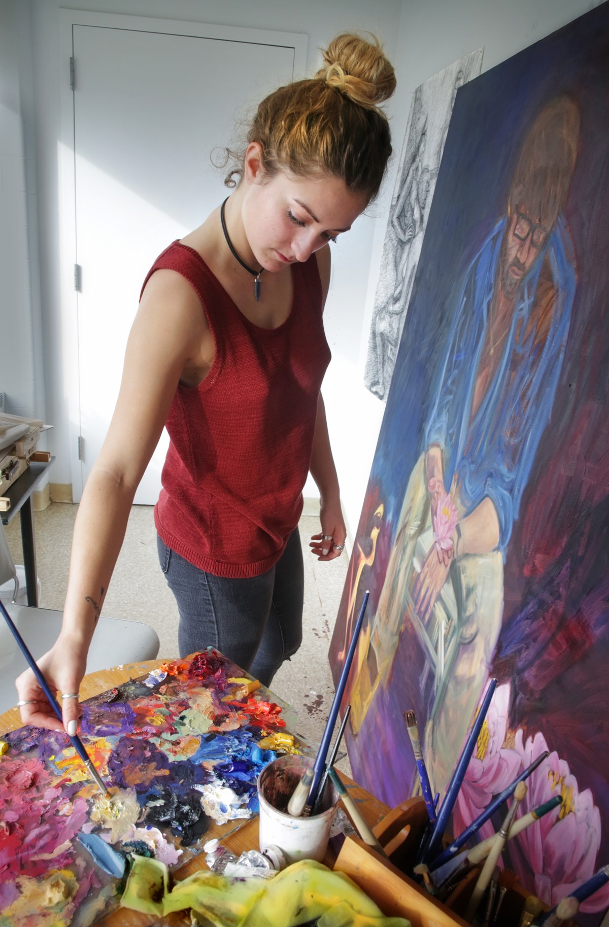 Art and design student painting in a UMass Lowell studio
