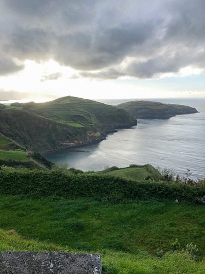 A beautiful, green hilly landscape touching the sea at sunset in Azores
