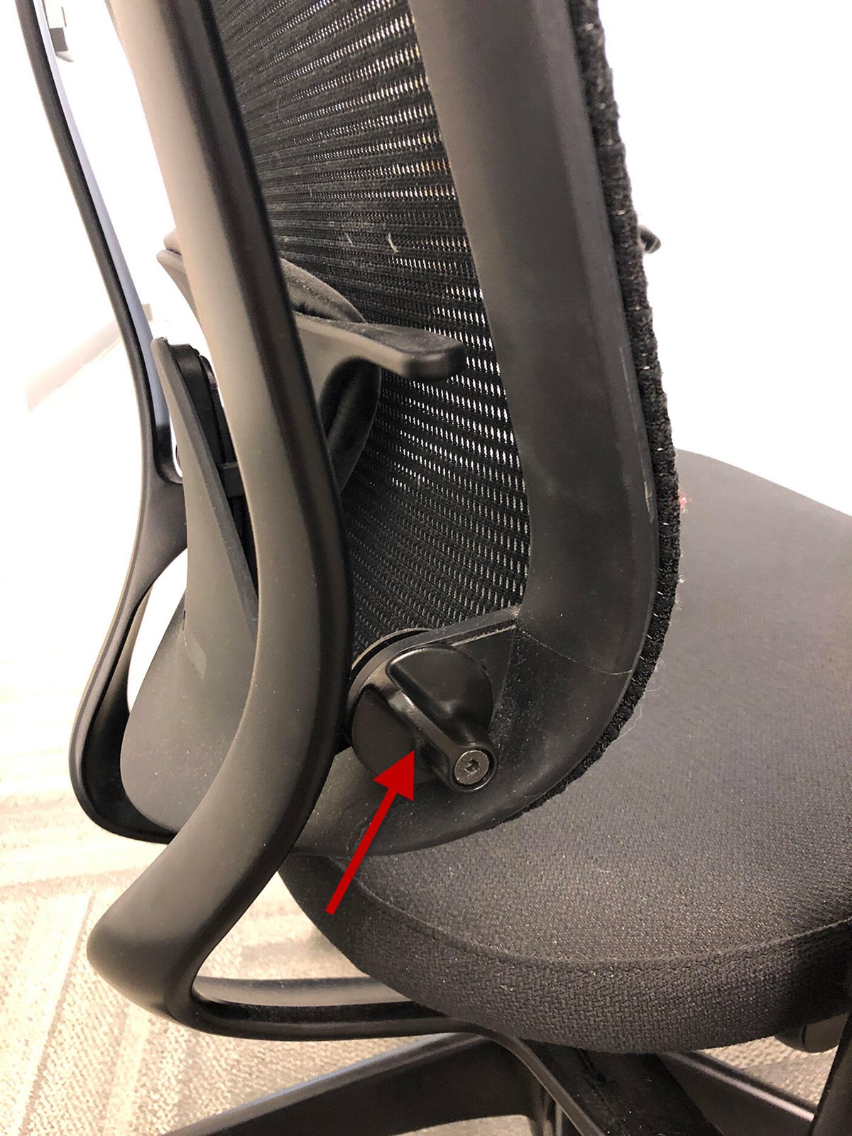 The back of a contessa chair with arrows pointing to the lever that engages and disengages the lumbar support. These levers can be found on the back side of the backrest on the bottom edges near the waste.