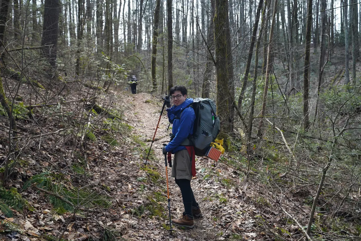 One person looks back and smiles while carrying his backpack on the Appalachian Trail.