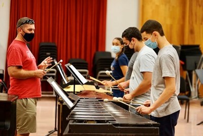 four camp participants play xylophones while a teacher looks on in a classroom