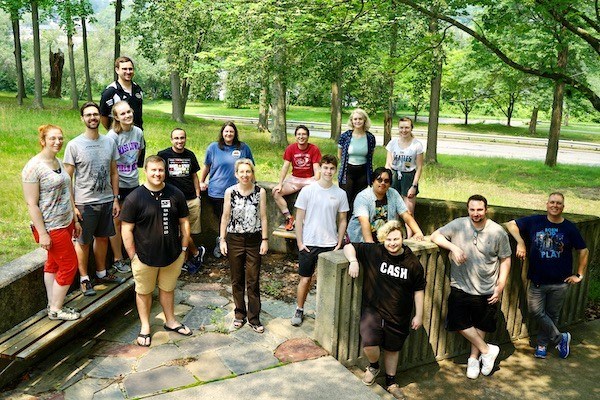 15 band camp counselors and the camp director pose for a photo outside