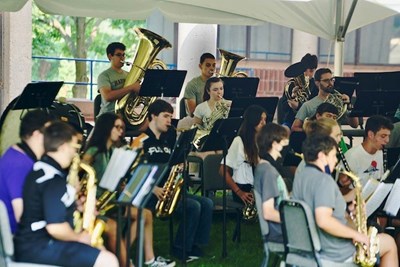 Students play brass instruments under a tent at band camp