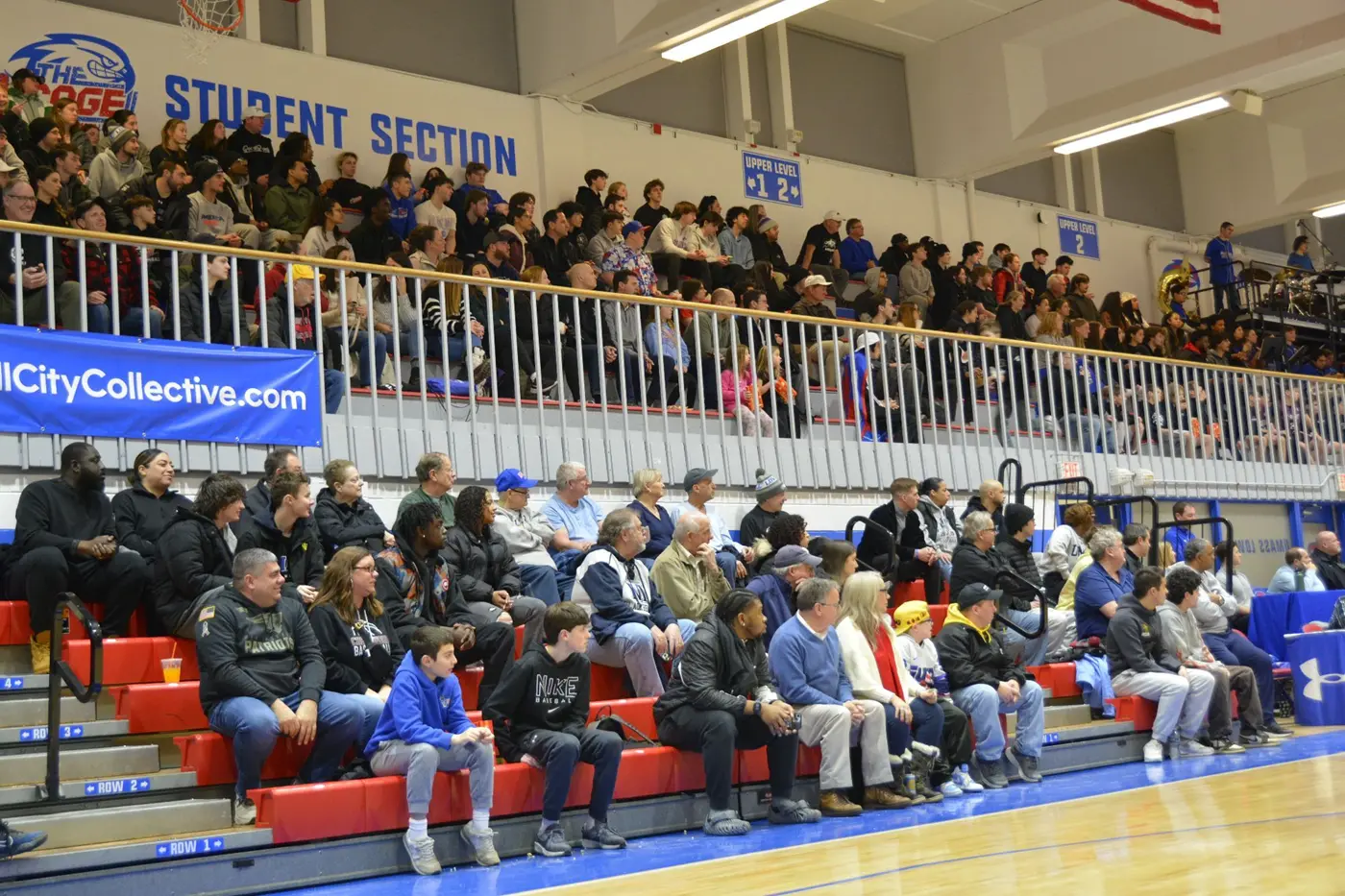 Basketball fans sit on wooden bleachers in a gymnasium