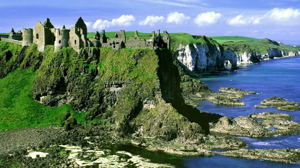 Castle ruins on green cliffs above the coast of Northern Ireland