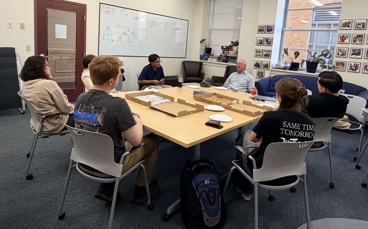 Bill Vaillancourt talks to Shah Academy students around a table during a Meet-and-Greet session.