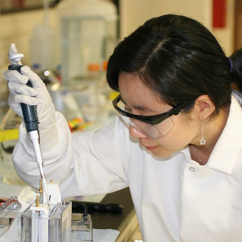 Biology research female putting liquid in test tube 