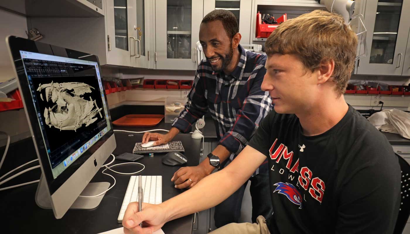 Professor and student view skull on computer screen in UMass Lowell biology lab