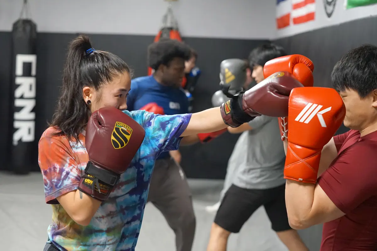 Two boxers wearing headgear fight in a boxing ring.