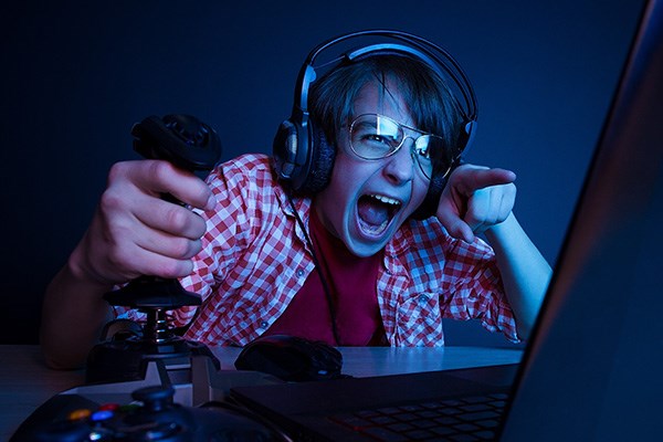 Teen wearing headphones excitedly playing video games