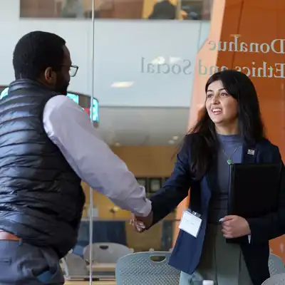 A business student shakes another person's hand at UMass Lowell's Manning School of Business.