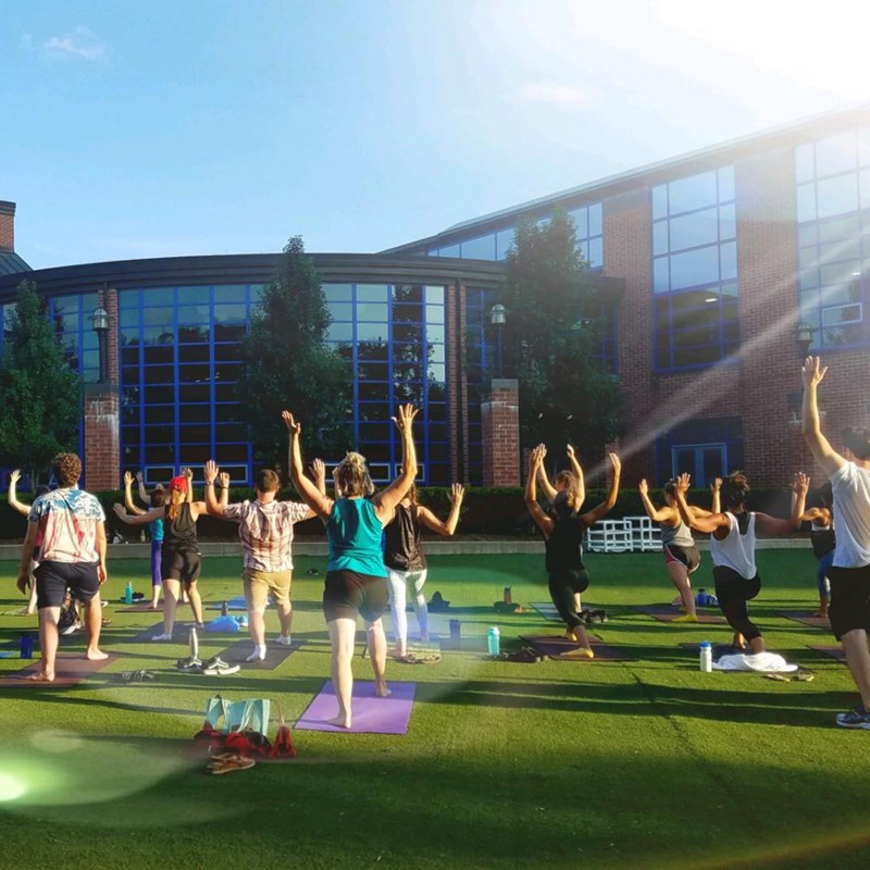 Students participate in an outdoor yoga class on the lawn of the Campus Recreation Center on a sunny afternoon