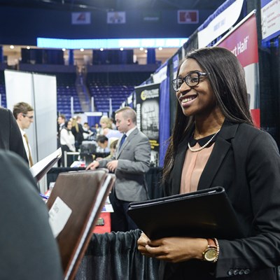 A female student smiles at the Career Fair