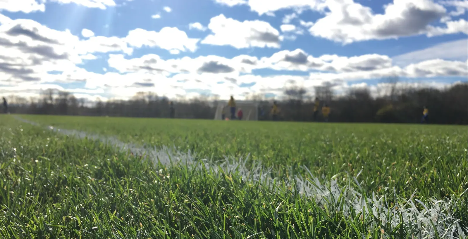Close up of a chalk line on grass field with fuzzy people in background