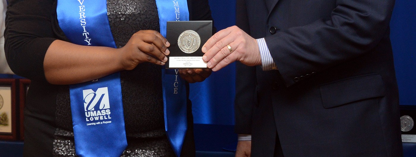 Close up image of Chancellor's Medal being held between two people. Photo from 2014.