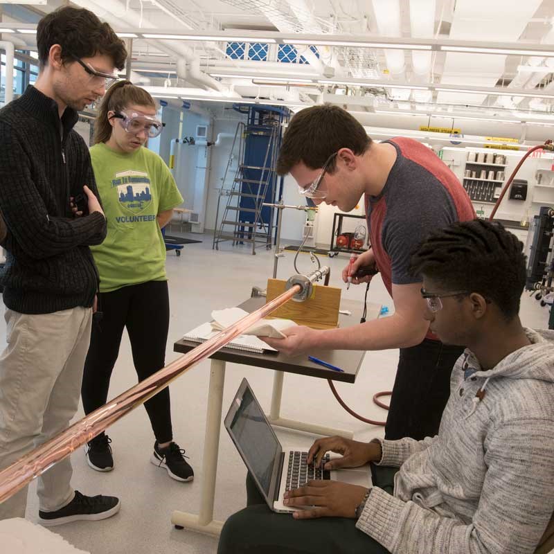 Group of students work with equipment and a laptop in a chemical engineering lab at UMass Lowell