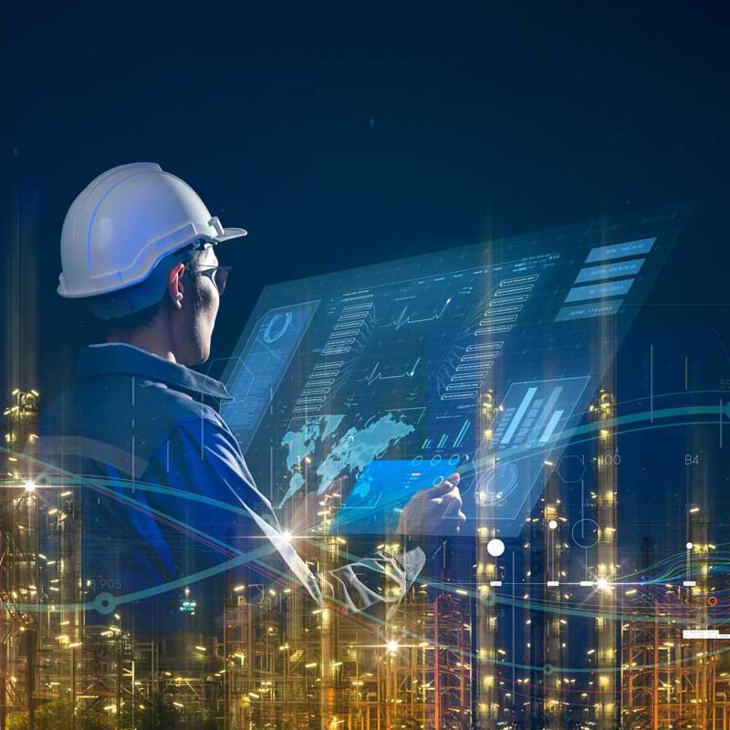Engineer wearing a hard hat and looking at a smart screen with a smart industry background