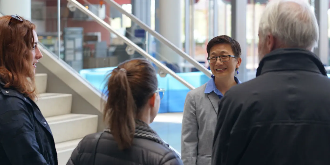 UMass Lowell Chancellor Julie Chen speaks with people in the lobby of University Crossing