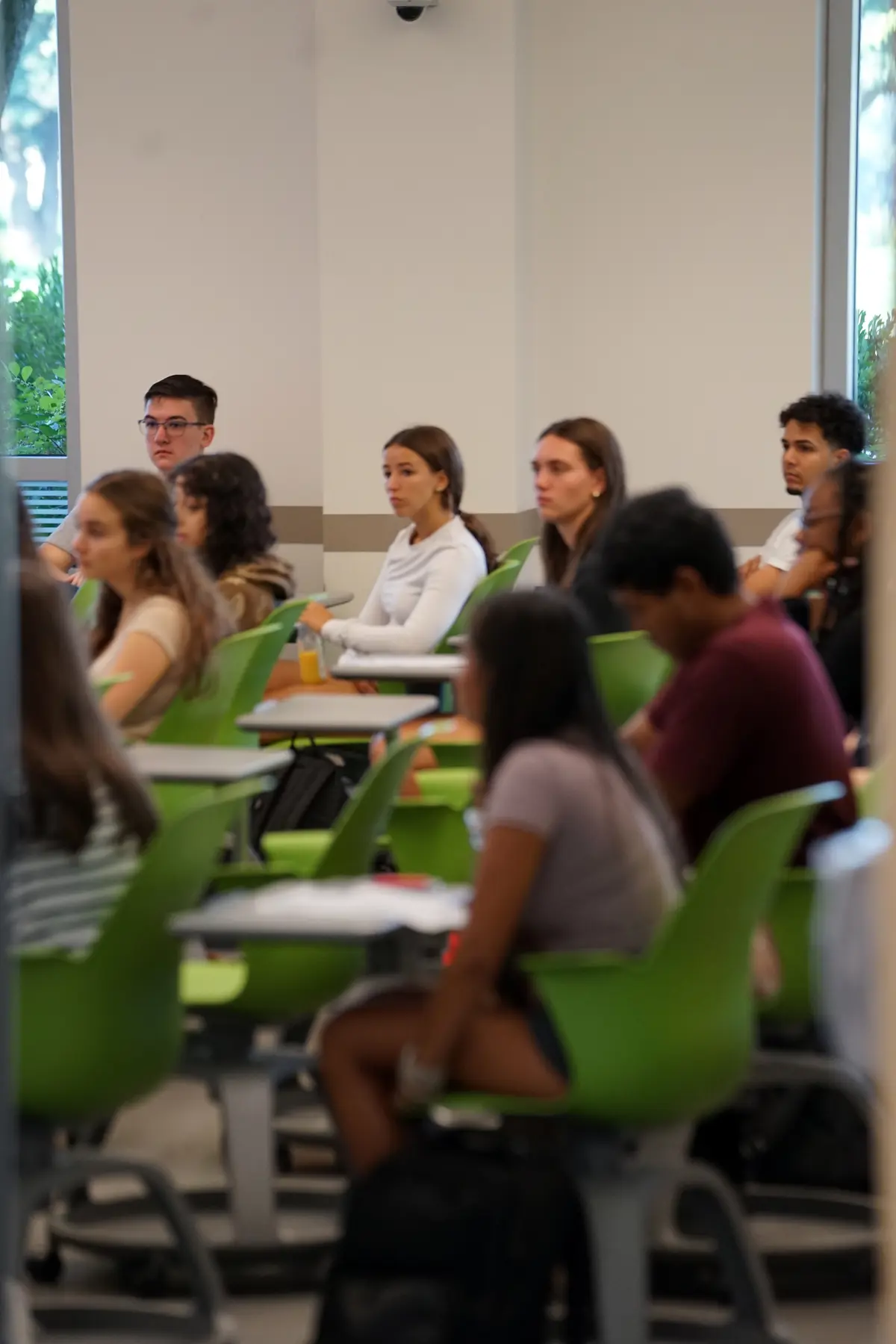 Students sitting in desks look toward the front of the classroom
