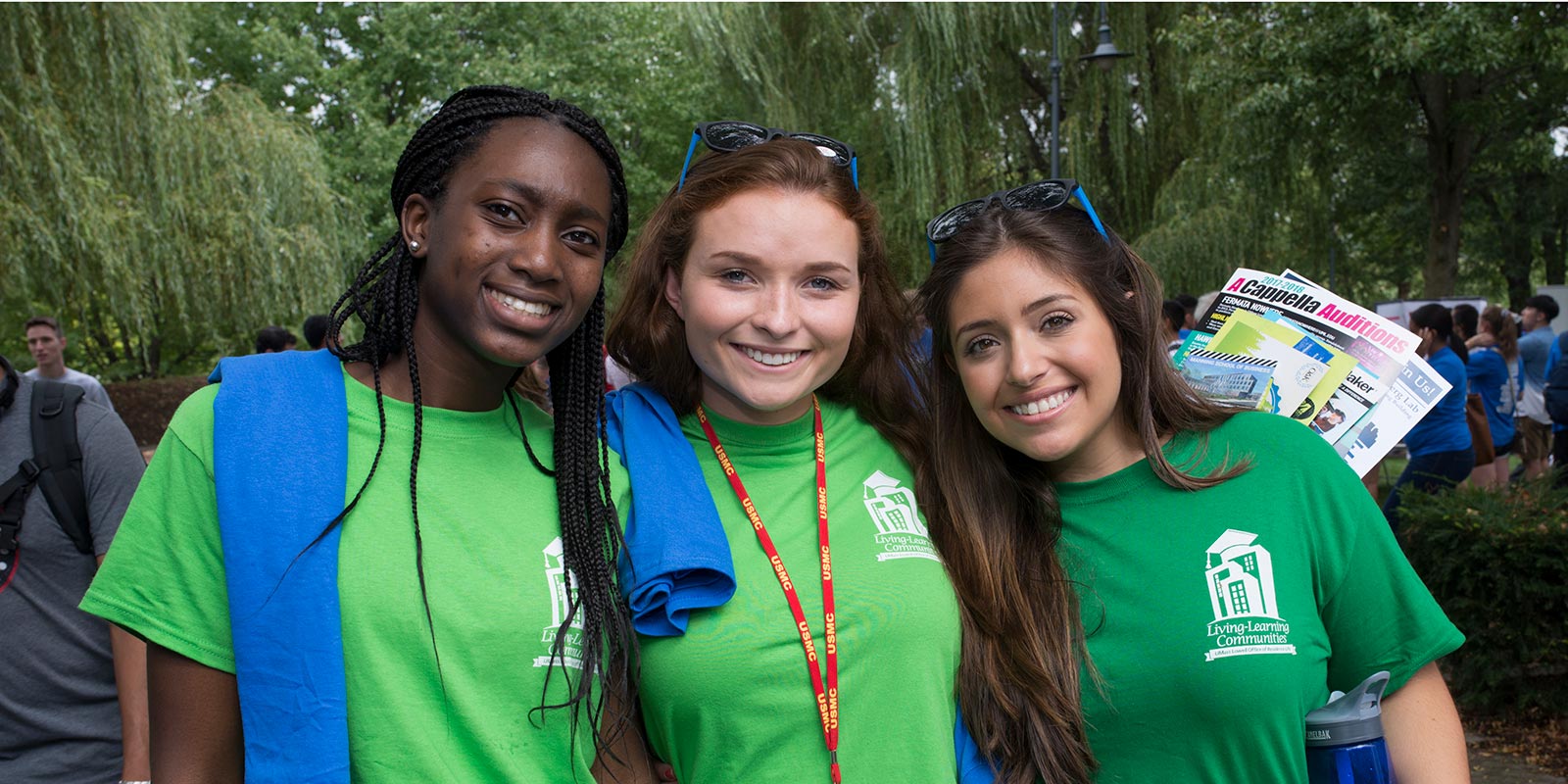 Three women wearing green Living and Learning Community T-shirts at the Club Fair