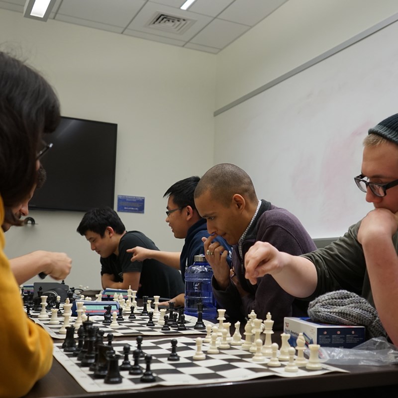 A group of students plays chess in the Club Hub at UML