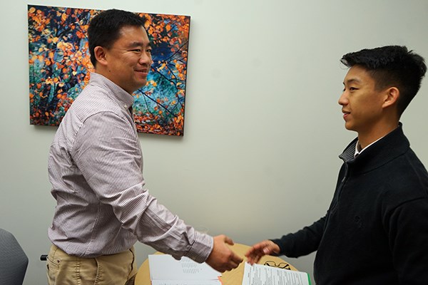 Alum Wentao Wang shakes hands with a student applying for a Pfizer co-op