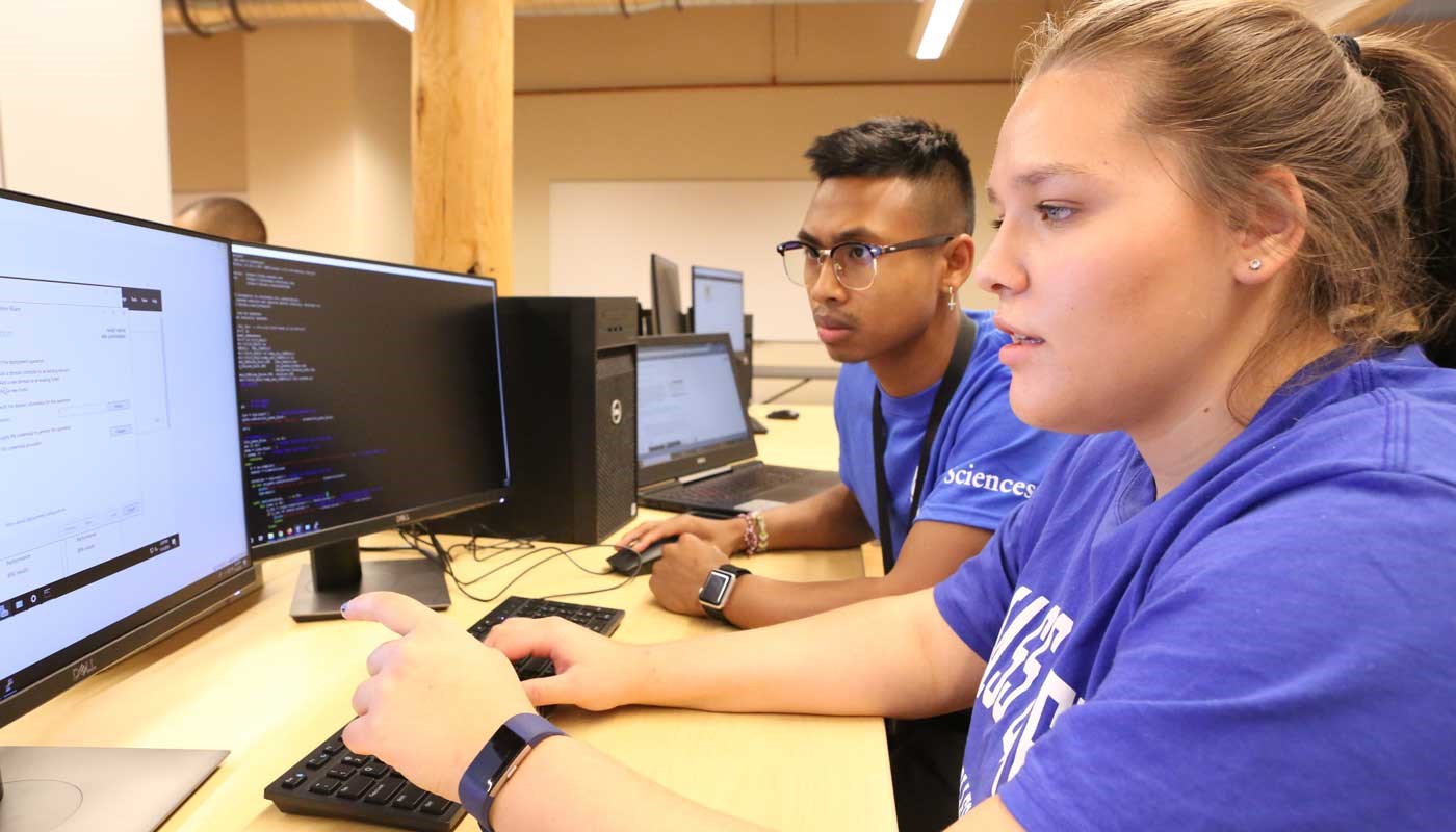 Two students look at a computer in a computer science classroom at UMass Lowell