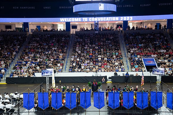 Several hundred students sit in an arena facing a stage