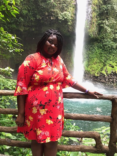 Melinda Duah outdoors in front of a tropical waterfall