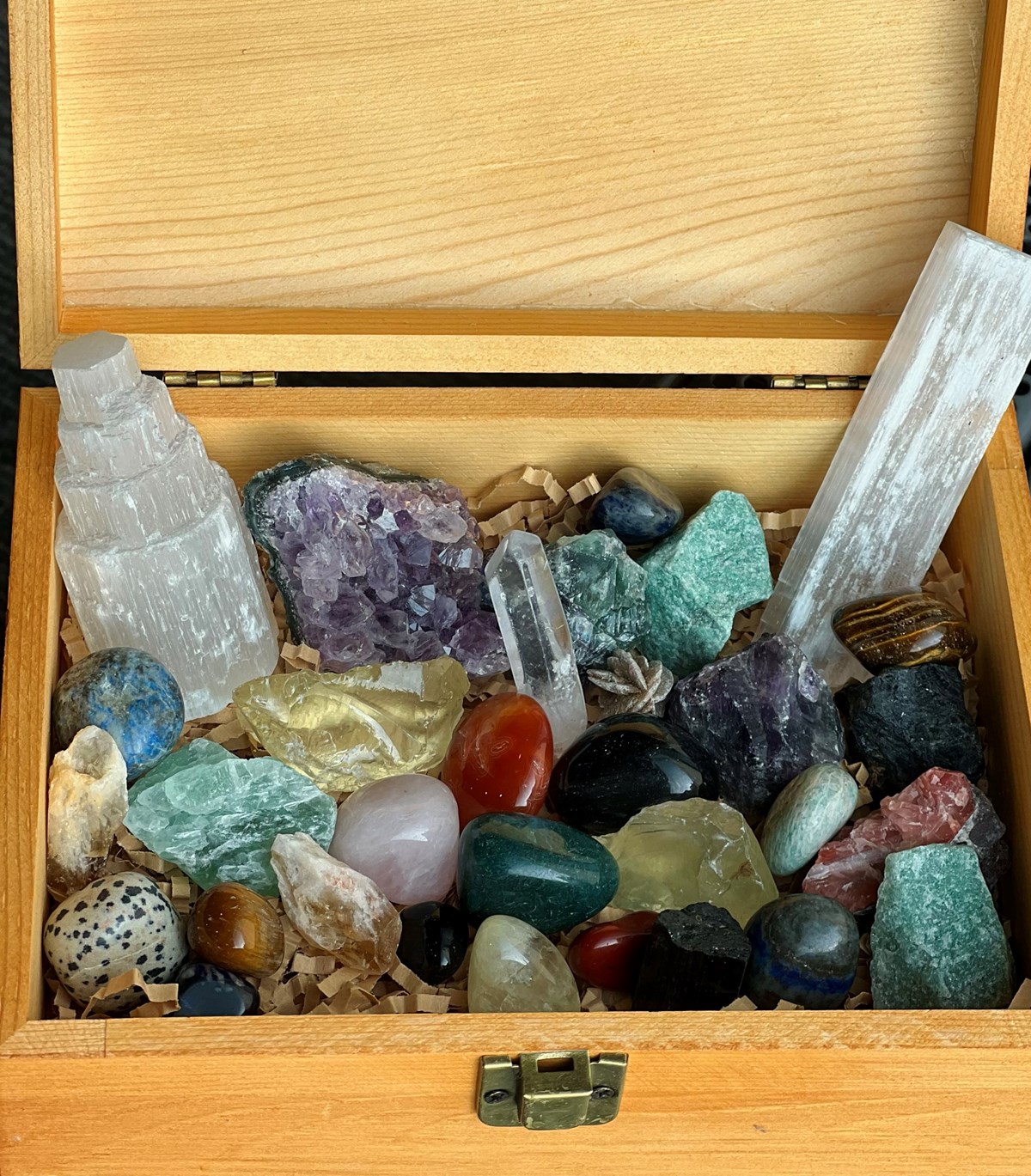 Several multicolored crystals sitting in wooden box