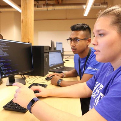 Two students in the UMass Lowell Cybersecurity program work at a computer.