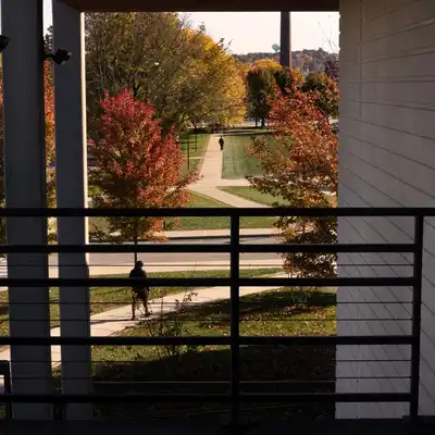 Students walking on paths in distance from dark balcony.