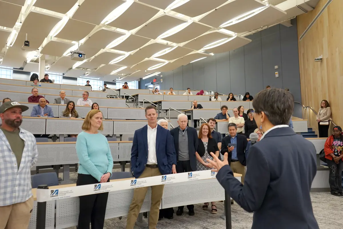 A woman in a blazer speaks to a people in a college lecture hall.