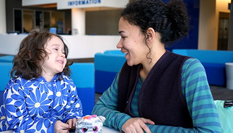 UMass Lowell student Denia Taylor sitting at a table at University Crossing with her daughter