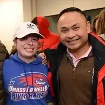 Woman in UMass Lowell River Hawks sweatshirt and baseball cap standing with man in ski jacket