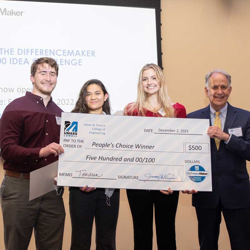 Three students and a professor hold an enlarged check for the People's Choice Winner at UMass Lowell DifferenceMaker competition