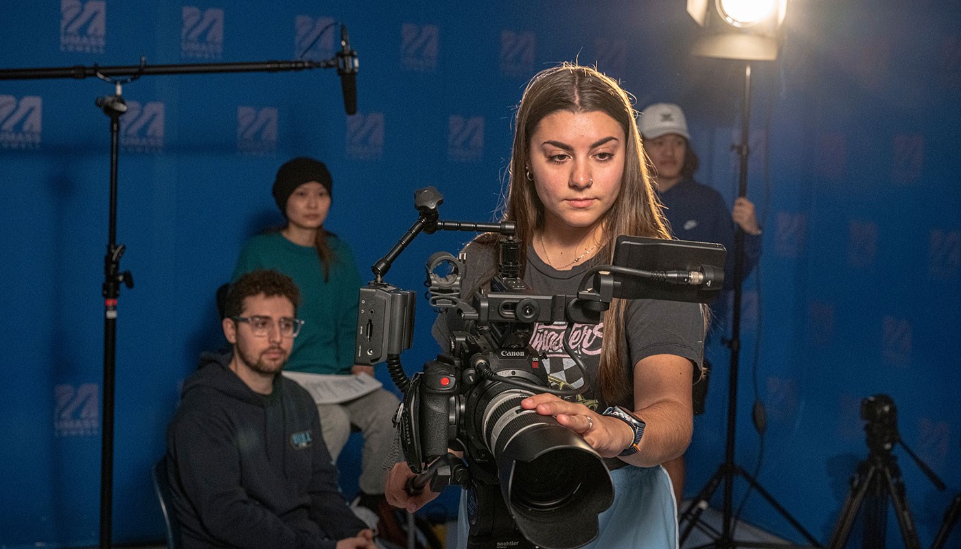 Digital media student focuses camera as her classmates look on