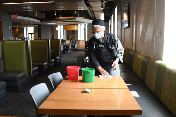 A dining hall employee sanitizes a table at Fox Dining Commons