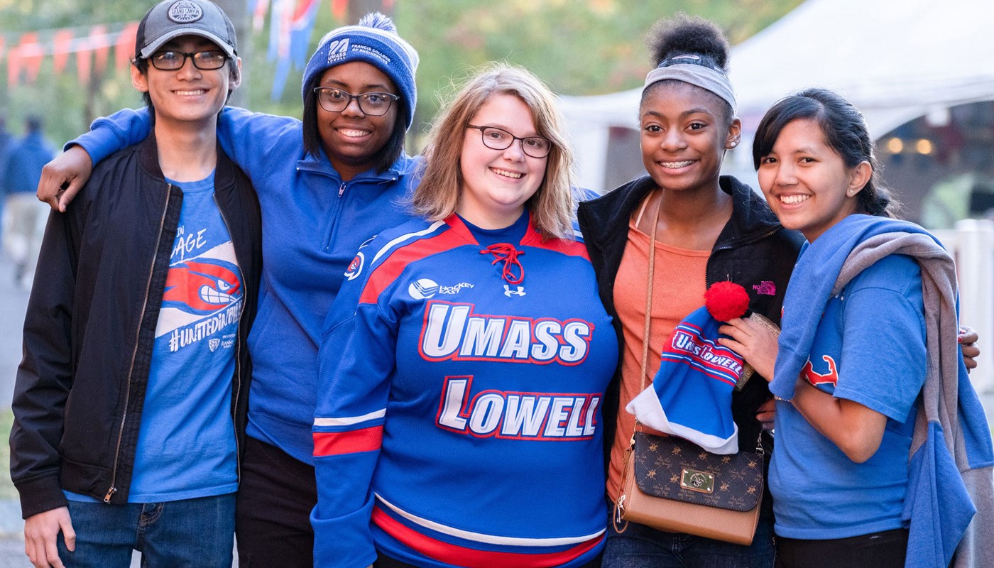 Five students wearing UMass Lowell shirts smile at camera