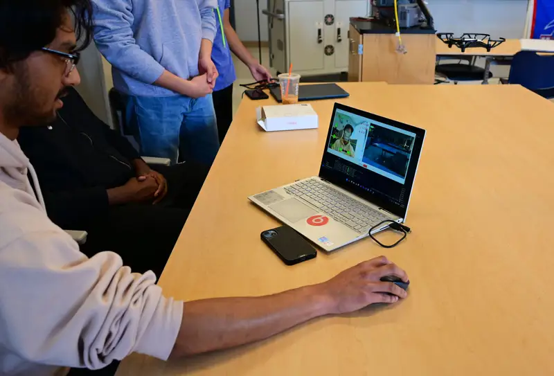 A capstone project team using a laptop with facial recognition software