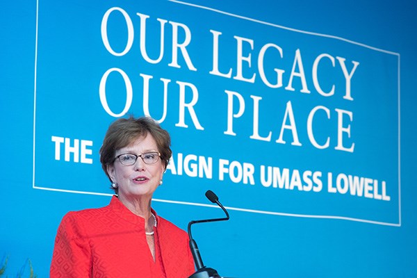 UMass Lowell Chancellor Jacquie Moloney in front of Our Legacy, Our Place banner