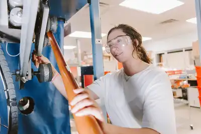 An engineering student uses lab equipment to shape a baseball bat at UMass Lowell.