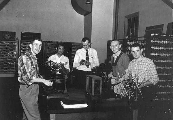 Male engineering students pose for a photo while working together in a group in 1956
