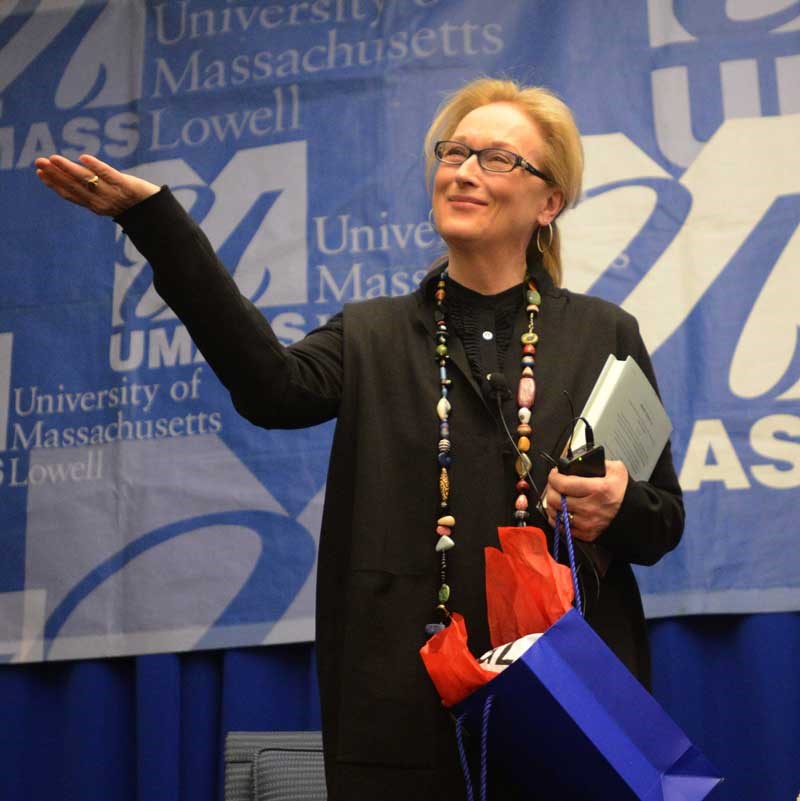 Meryl Street holding a book in front of the UMass banner