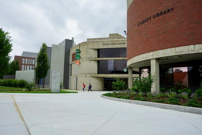 Two people walk on the repaved entry plaza on South Campus