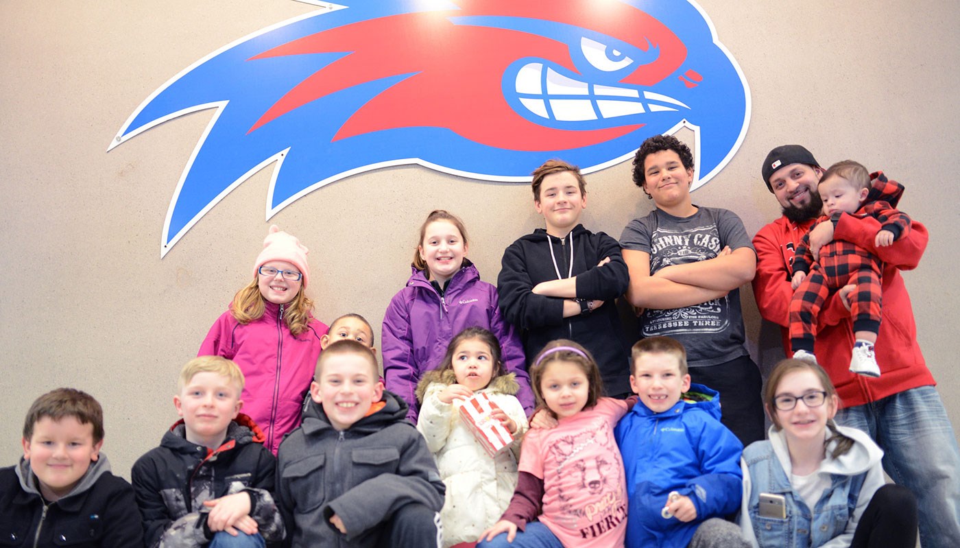 Group of young children and a dad holding a baby in front of River Hawk logo
